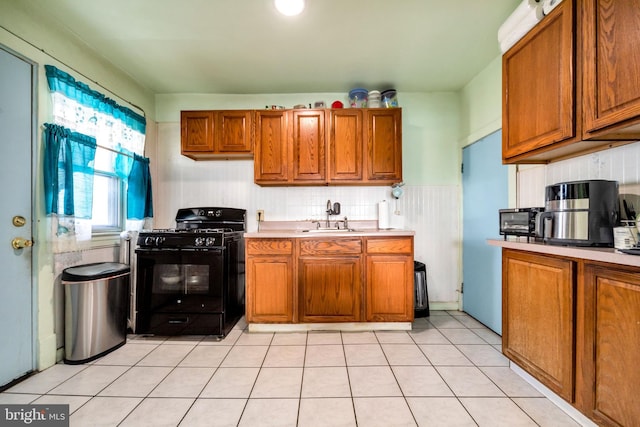 kitchen featuring light tile patterned flooring, black gas range oven, sink, and backsplash