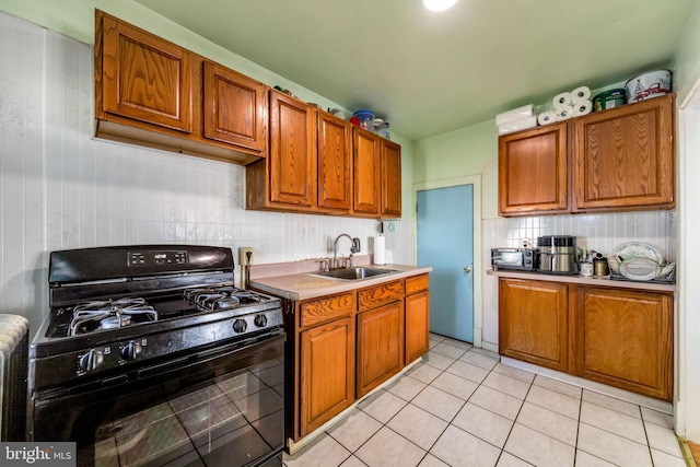 kitchen featuring gas stove, sink, light tile patterned floors, and backsplash