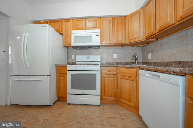 kitchen with white appliances, stone countertops, sink, and backsplash