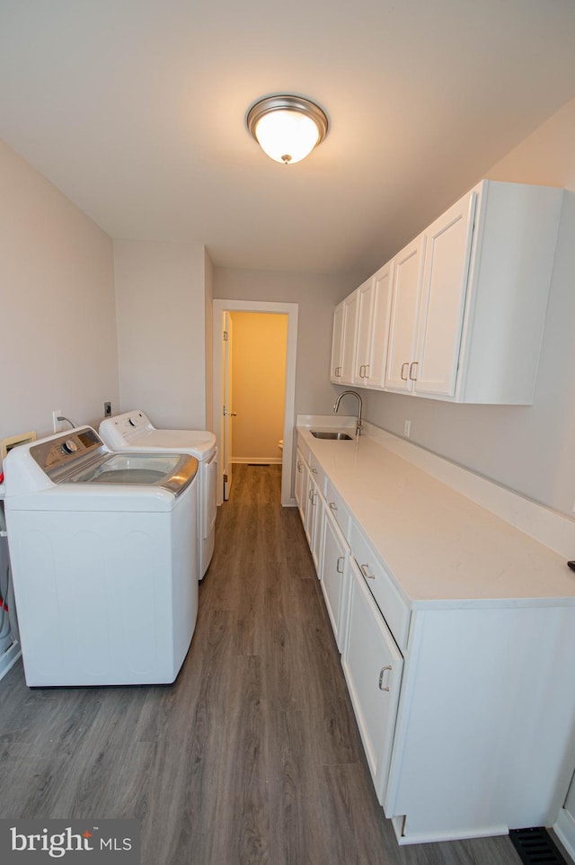 washroom with cabinets, sink, independent washer and dryer, and dark hardwood / wood-style floors