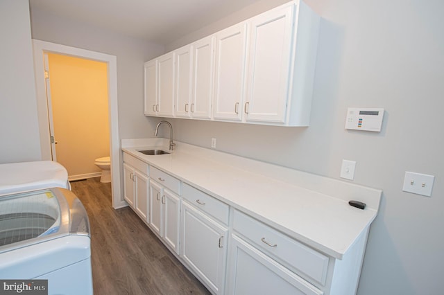 laundry area featuring cabinets, sink, washer and clothes dryer, and dark hardwood / wood-style floors