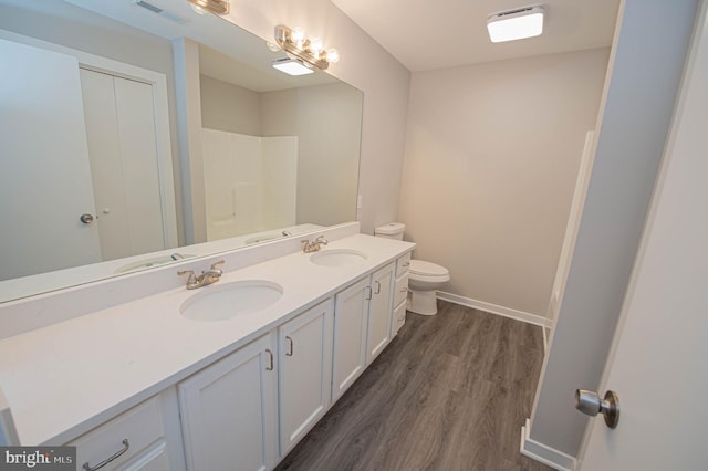 bathroom featuring wood-type flooring, walk in shower, vanity, and toilet