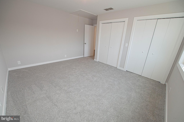 unfurnished bedroom with multiple closets and carpet