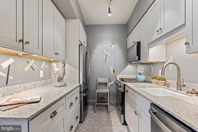 kitchen featuring white cabinetry, appliances with stainless steel finishes, sink, and light stone counters