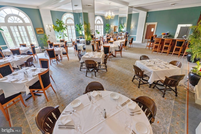 carpeted dining space with crown molding and a chandelier