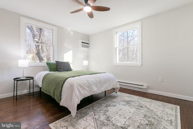 bedroom with a wall mounted AC, a baseboard heating unit, dark wood-type flooring, and ceiling fan