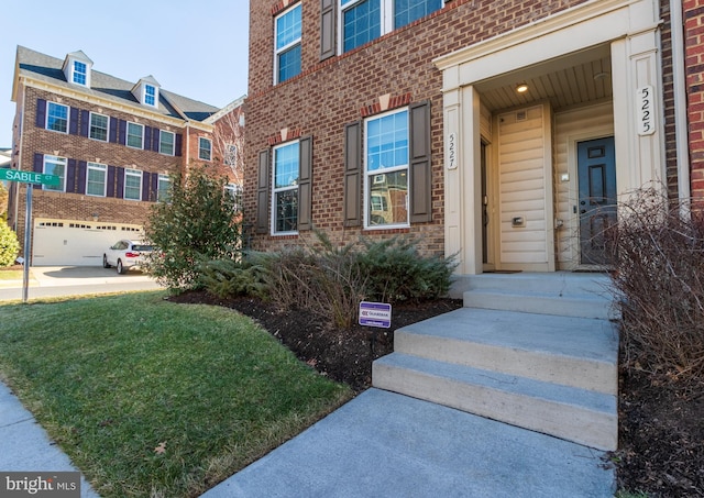 view of exterior entry featuring a yard and a garage