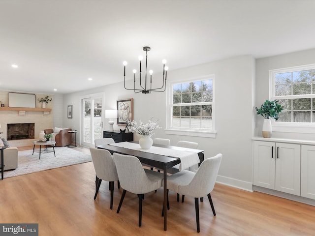 dining area featuring a wealth of natural light, a fireplace, light hardwood / wood-style floors, and a chandelier