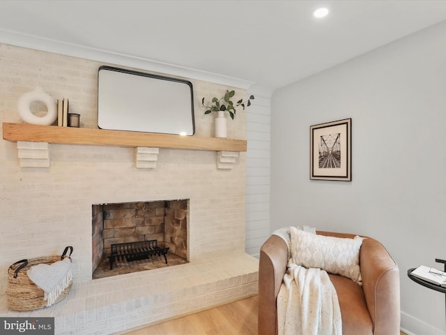 living area featuring wood-type flooring and a brick fireplace