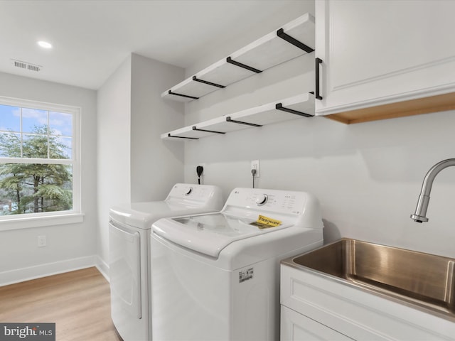 washroom with sink, cabinets, washer and dryer, and light wood-type flooring