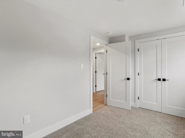 unfurnished bedroom with light carpet and a closet