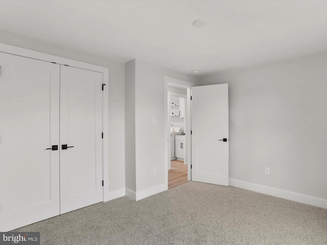 unfurnished bedroom featuring washer / clothes dryer, light colored carpet, and a closet