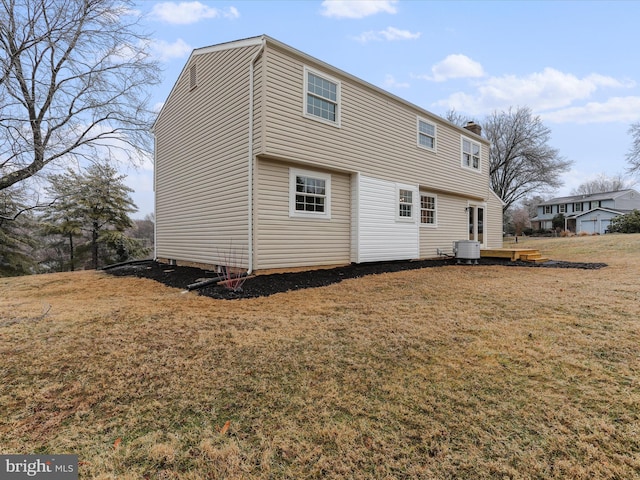 back of property featuring central air condition unit and a lawn