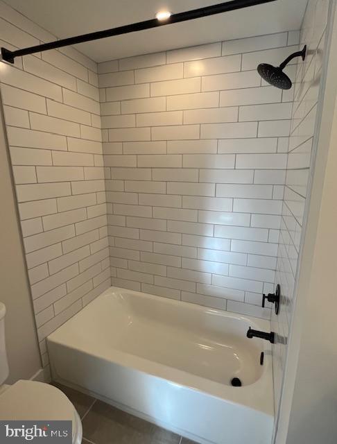 bathroom featuring tiled shower / bath combo and toilet