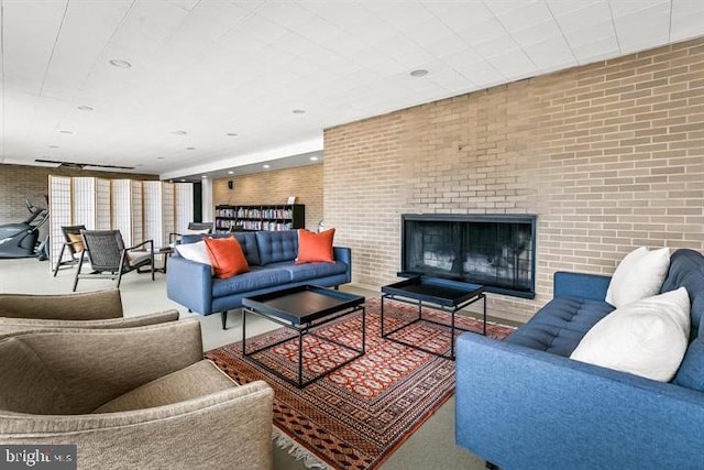 carpeted living room with a brick fireplace and brick wall