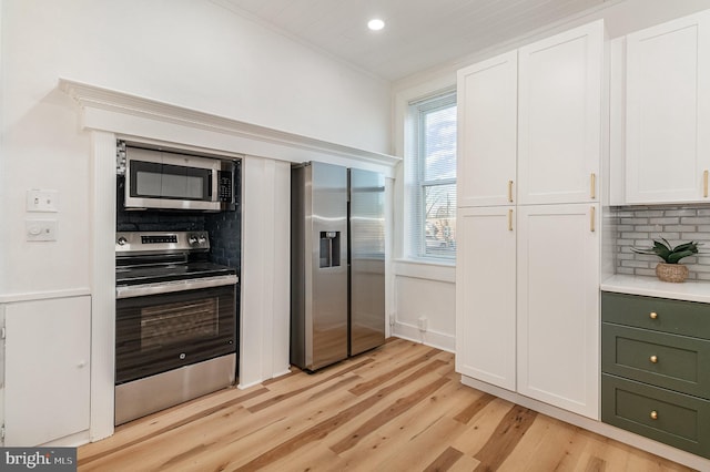 kitchen featuring backsplash, light hardwood / wood-style flooring, white cabinets, and appliances with stainless steel finishes