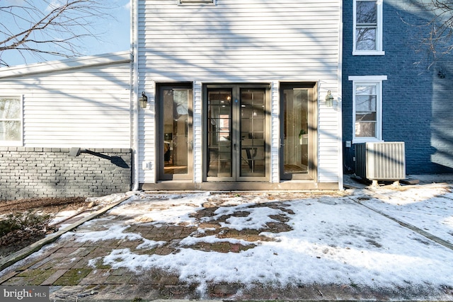 snow covered property entrance featuring central AC