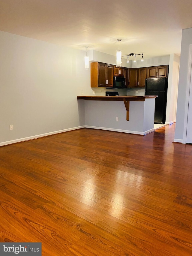 kitchen featuring dark hardwood / wood-style floors, a breakfast bar, hanging light fixtures, and black appliances