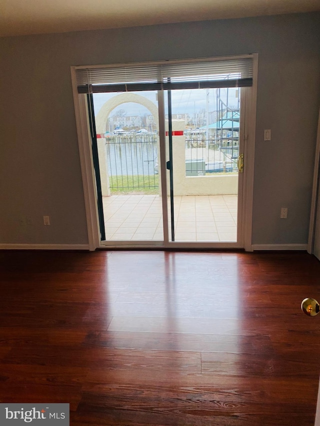 unfurnished room featuring a water view and dark wood-type flooring