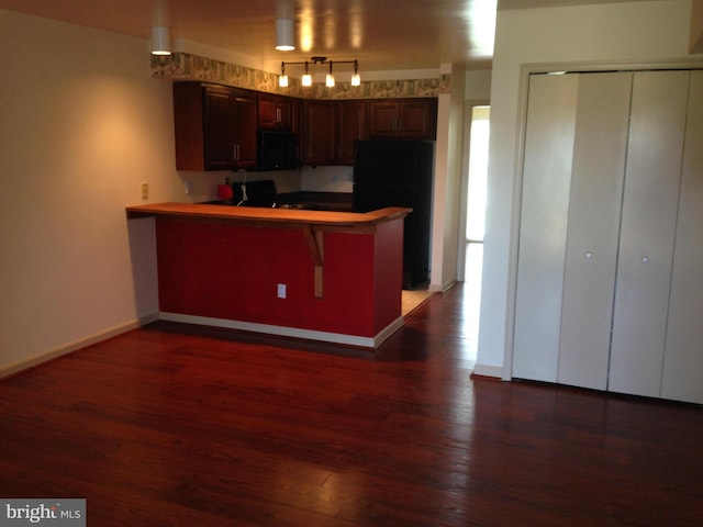 kitchen with black refrigerator, dark hardwood / wood-style flooring, and kitchen peninsula