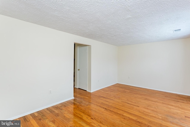 spare room with hardwood / wood-style floors and a textured ceiling