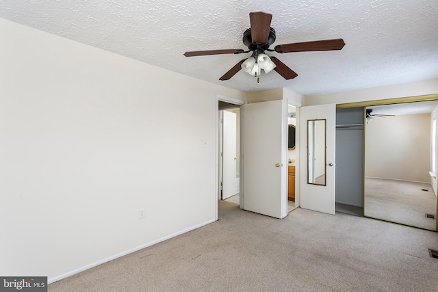 unfurnished bedroom with light carpet, ceiling fan, a closet, and a textured ceiling