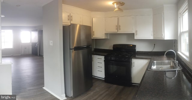 kitchen featuring black gas range oven, sink, stainless steel refrigerator, dark hardwood / wood-style floors, and white cabinets