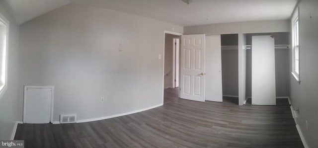 unfurnished bedroom featuring vaulted ceiling, dark wood-type flooring, and a closet