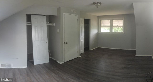 unfurnished bedroom with lofted ceiling and dark hardwood / wood-style floors