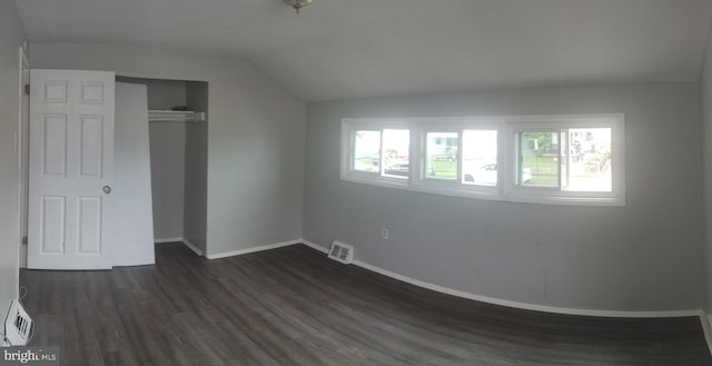 unfurnished bedroom featuring vaulted ceiling, dark wood-type flooring, and a closet