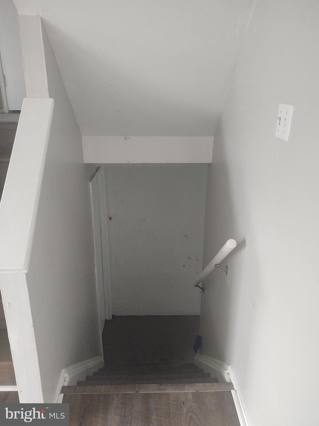 stairway with vaulted ceiling and hardwood / wood-style floors