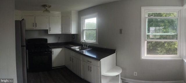 kitchen featuring white cabinetry, gas stove, sink, and stainless steel refrigerator