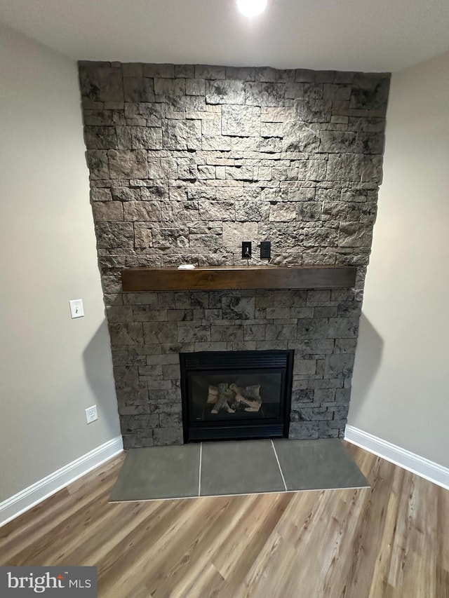 details with hardwood / wood-style floors and a stone fireplace