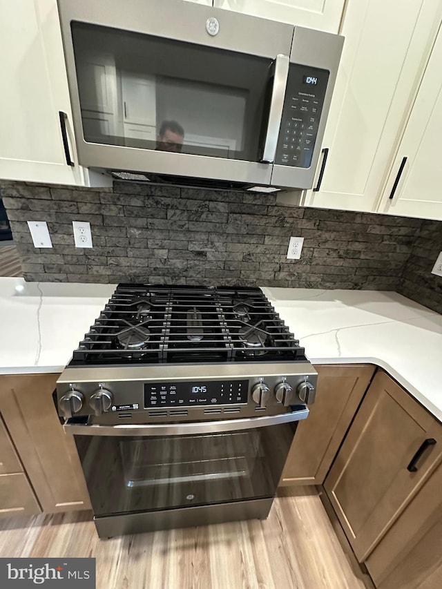 room details featuring tasteful backsplash, light hardwood / wood-style flooring, light stone countertops, and gas range oven