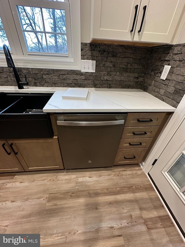 kitchen with dishwasher, light wood-type flooring, white cabinets, and light stone counters