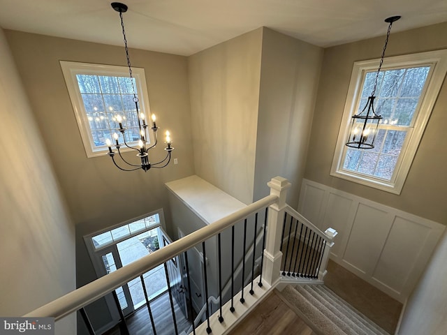 stairway featuring wood-type flooring, plenty of natural light, and a chandelier