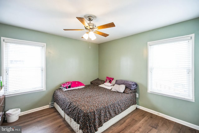 bedroom with multiple windows, dark wood-type flooring, and ceiling fan