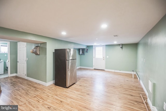 kitchen with washer / dryer, stainless steel refrigerator, and light wood-type flooring