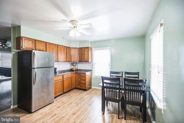 kitchen with backsplash, stainless steel fridge, light hardwood / wood-style floors, and ceiling fan