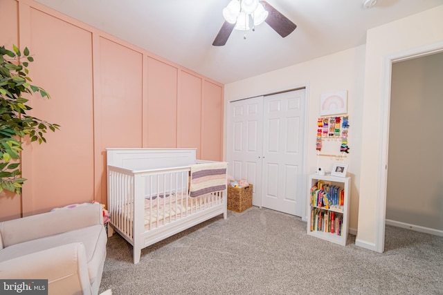 carpeted bedroom featuring a crib, ceiling fan, and a closet