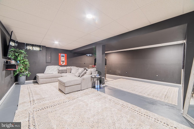 living room with a paneled ceiling and concrete flooring