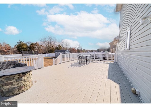 wooden deck featuring a trampoline and a storage unit