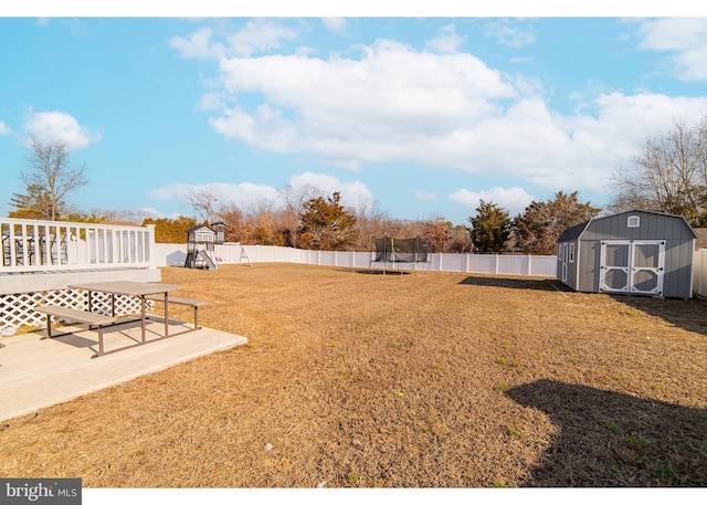 view of yard with a trampoline, a patio area, a playground, and a shed