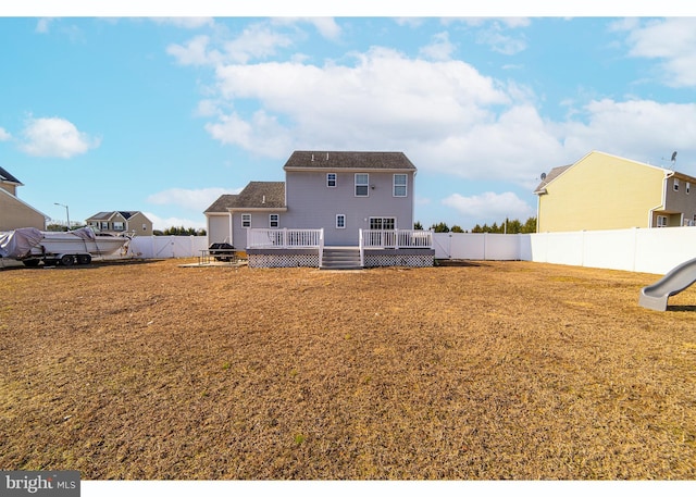 rear view of house featuring a yard, a deck, and a playground