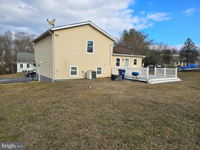 back of property featuring central AC unit, a deck, and a lawn