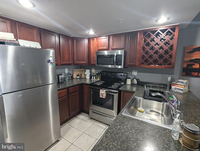 kitchen with dark stone countertops, sink, light tile patterned flooring, and appliances with stainless steel finishes