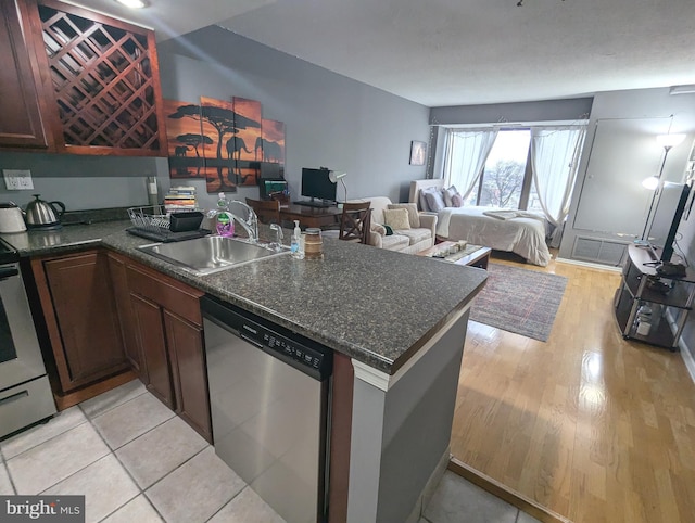 kitchen featuring appliances with stainless steel finishes, kitchen peninsula, sink, and light wood-type flooring