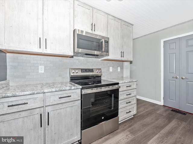 kitchen with tasteful backsplash, visible vents, dark wood-type flooring, light stone countertops, and stainless steel appliances