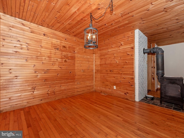 interior space featuring a wood stove, wooden ceiling, an inviting chandelier, and wood finished floors