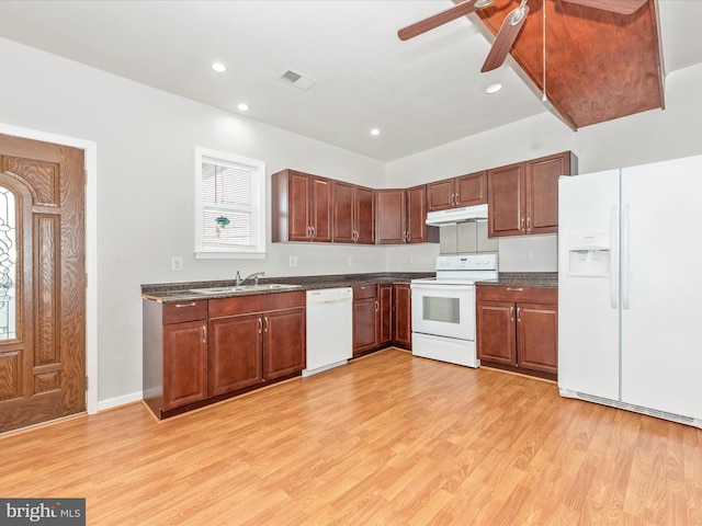 kitchen with white appliances, visible vents, dark countertops, under cabinet range hood, and a sink